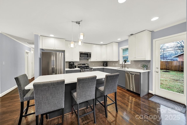 kitchen featuring a kitchen island, white cabinetry, appliances with stainless steel finishes, and pendant lighting