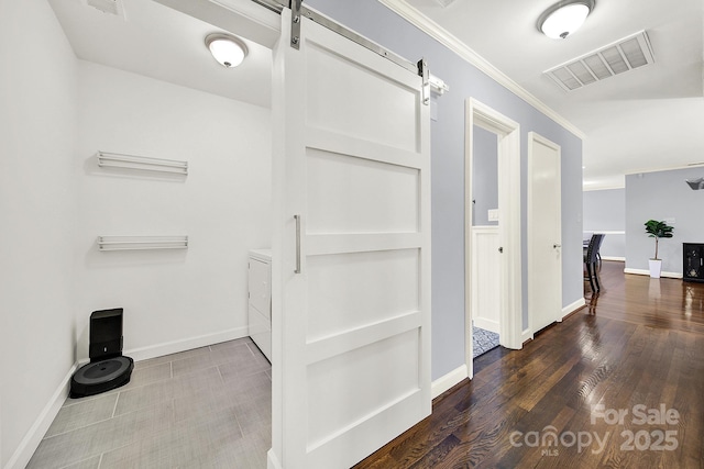 hall featuring dark hardwood / wood-style flooring, crown molding, separate washer and dryer, and a barn door