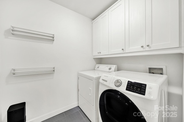 clothes washing area with dark tile patterned floors, cabinets, and washing machine and clothes dryer