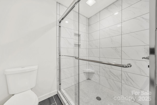 bathroom featuring a shower with shower door and toilet