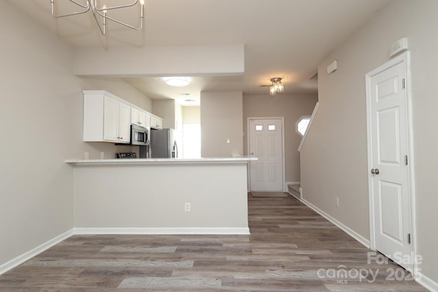 kitchen with white cabinets, light wood-type flooring, appliances with stainless steel finishes, and kitchen peninsula