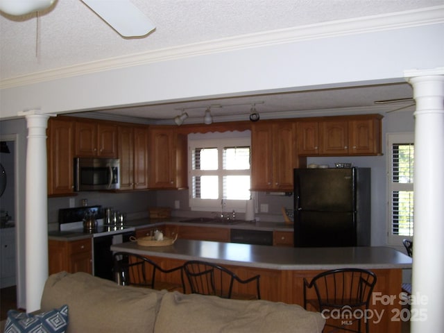 kitchen with sink, crown molding, black appliances, a textured ceiling, and ornate columns