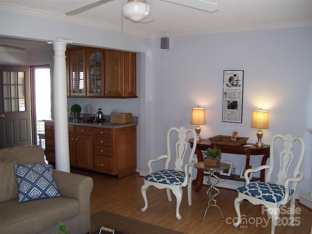 living room featuring hardwood / wood-style floors, crown molding, decorative columns, and ceiling fan