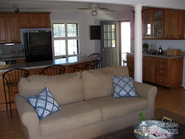 living room with ornate columns, ceiling fan, wood-type flooring, and a wealth of natural light