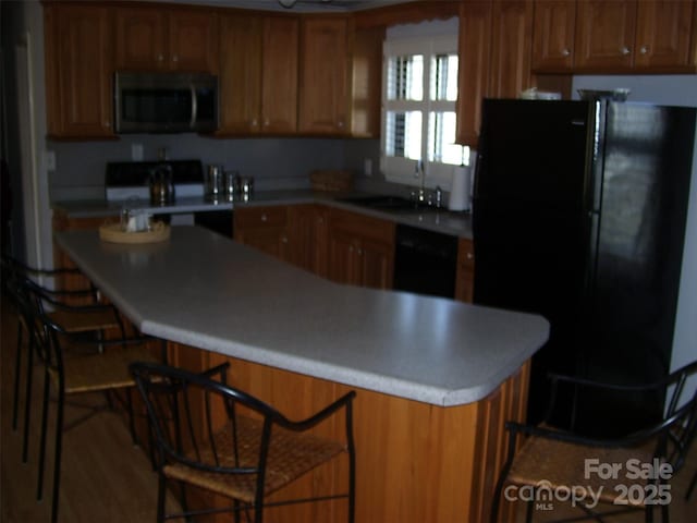 kitchen featuring sink, black appliances, and a kitchen bar