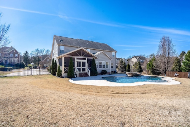 rear view of house with a fenced in pool, a patio, a sunroom, and a yard