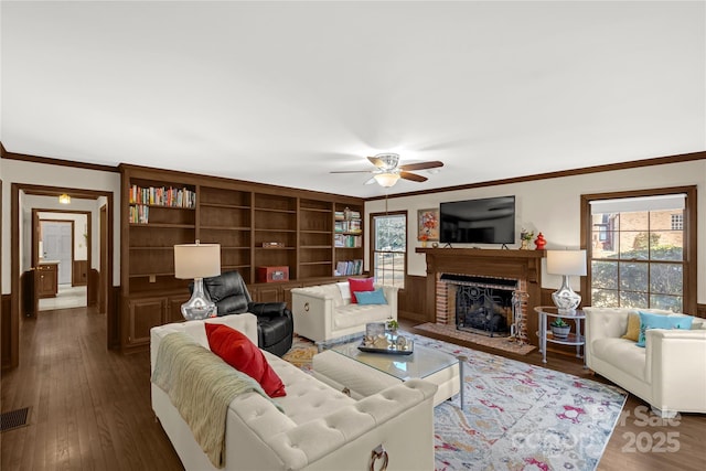 living room with ornamental molding, dark hardwood / wood-style flooring, a brick fireplace, and a wealth of natural light