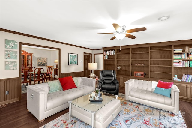 living room featuring crown molding, dark wood-type flooring, built in features, and ceiling fan