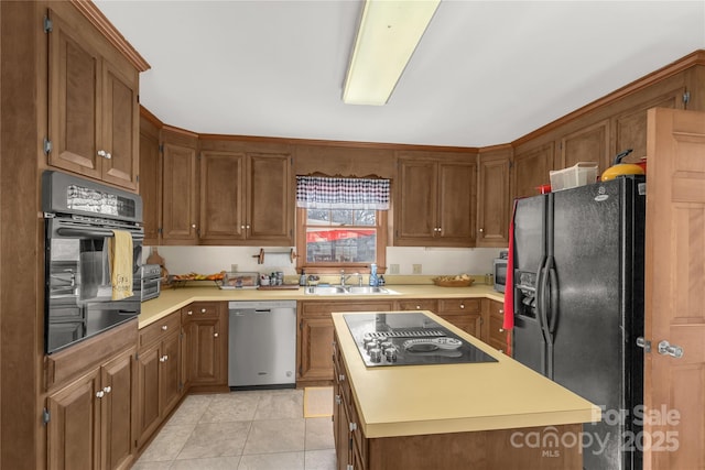 kitchen featuring sink, light tile patterned floors, black appliances, and a center island