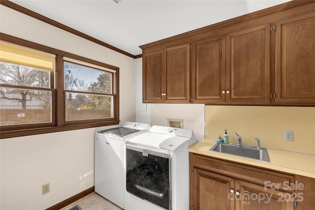 clothes washing area with sink, ornamental molding, cabinets, and washing machine and clothes dryer