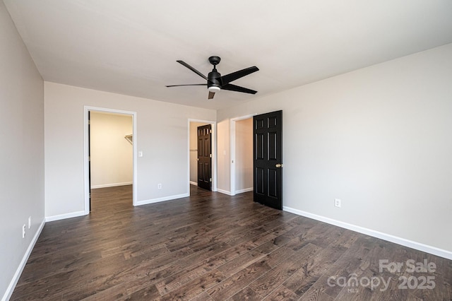 unfurnished bedroom with ceiling fan, a walk in closet, dark hardwood / wood-style floors, and a closet