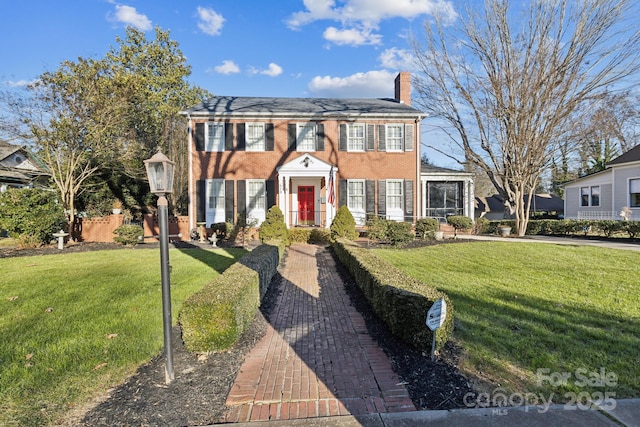 view of front of house with a front yard, brick siding, and a chimney