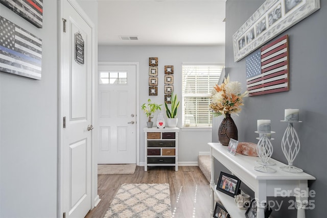 entryway featuring visible vents, baseboards, and wood finished floors