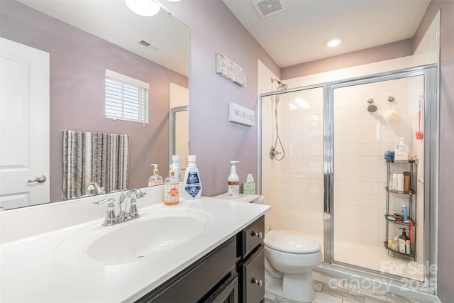 bathroom featuring toilet, a stall shower, visible vents, and vanity