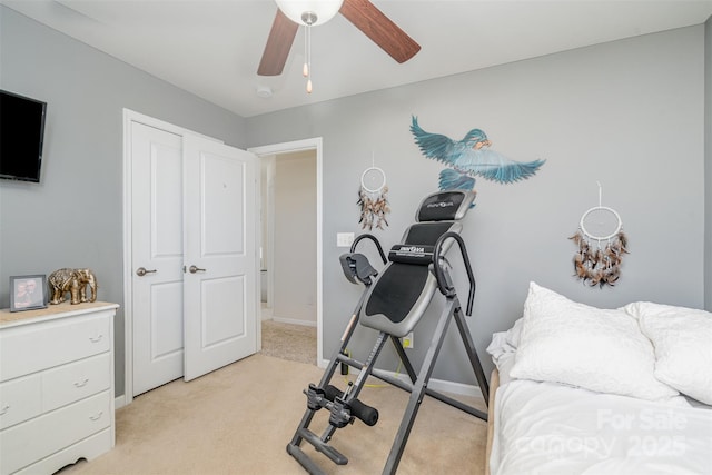 exercise area featuring light carpet, a ceiling fan, and baseboards