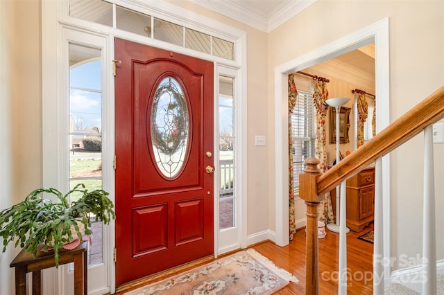 entryway featuring ornamental molding, plenty of natural light, stairway, and wood finished floors