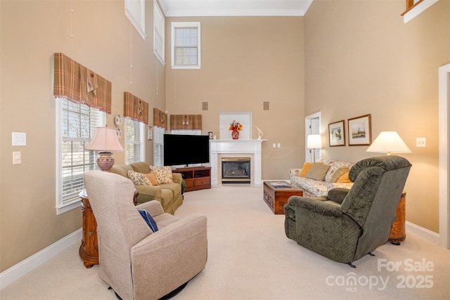 living area with carpet floors, baseboards, ornamental molding, and a glass covered fireplace