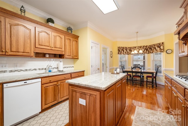 kitchen featuring crown molding, light wood finished floors, decorative backsplash, white dishwasher, and a sink