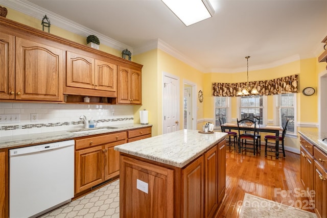 kitchen featuring white dishwasher, a sink, light wood-type flooring, brown cabinets, and crown molding