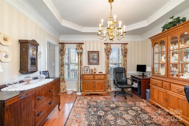 home office with a tray ceiling, wallpapered walls, light wood-style flooring, and an inviting chandelier