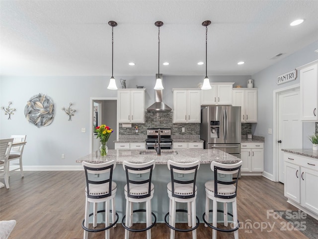 kitchen featuring sink, a kitchen island with sink, white cabinetry, stainless steel appliances, and decorative light fixtures