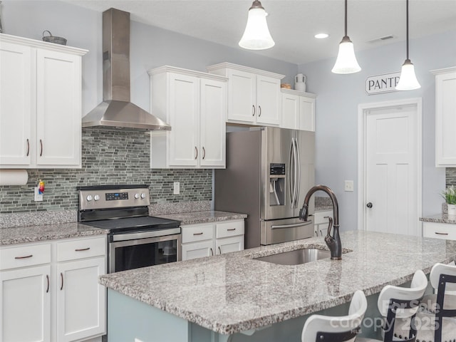 kitchen with wall chimney exhaust hood, sink, decorative light fixtures, a center island with sink, and appliances with stainless steel finishes