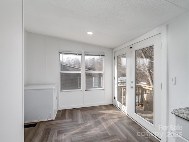 interior space with dark parquet flooring, a textured ceiling, and french doors