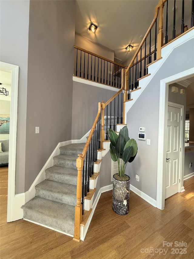 stairs featuring a towering ceiling and hardwood / wood-style flooring