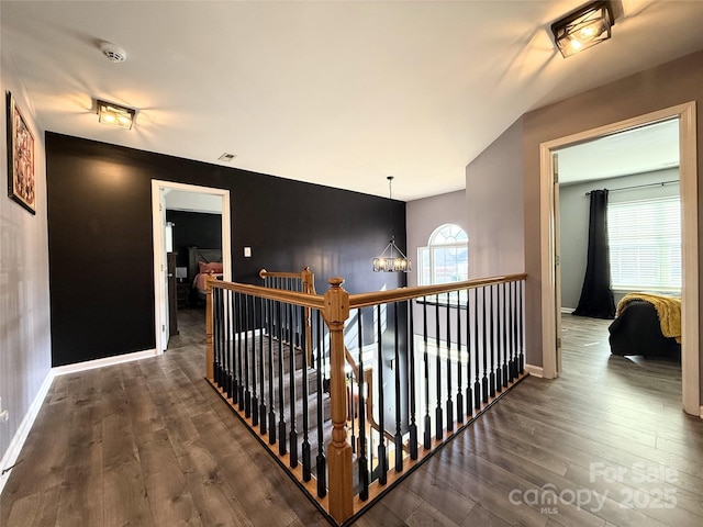 hallway with an inviting chandelier and dark hardwood / wood-style flooring