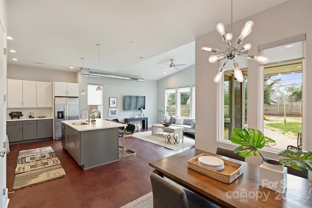 kitchen with decorative light fixtures, white cabinetry, gray cabinetry, stainless steel fridge, and a center island with sink