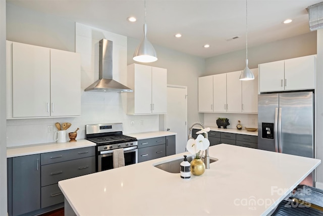 kitchen with pendant lighting, wall chimney range hood, appliances with stainless steel finishes, gray cabinetry, and white cabinets