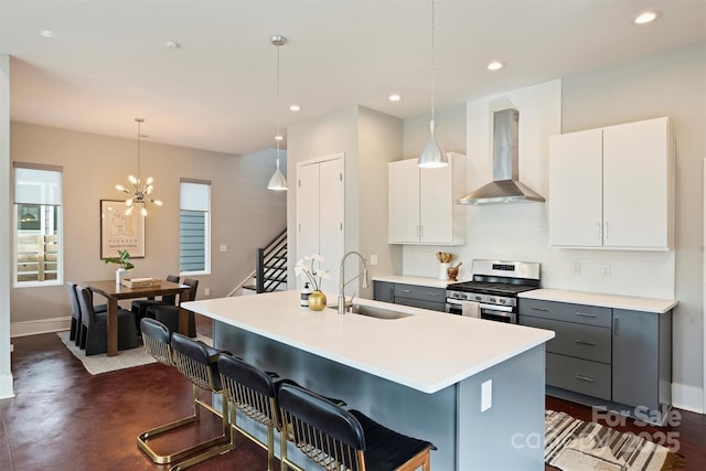 kitchen with pendant lighting, wall chimney range hood, gray cabinets, white cabinetry, and stainless steel range with gas stovetop