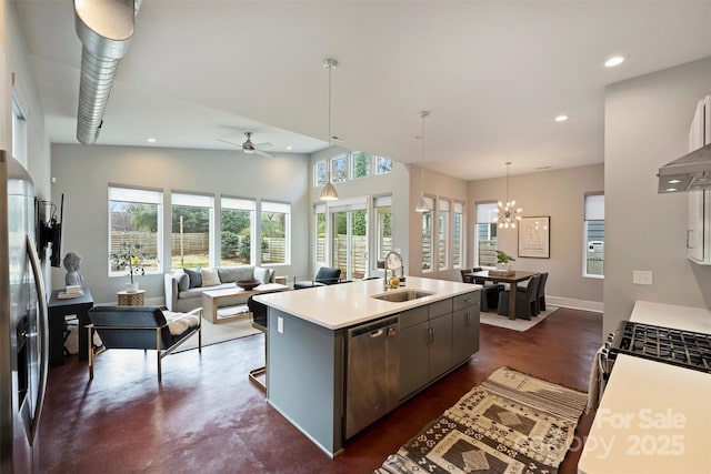 kitchen featuring appliances with stainless steel finishes, ceiling fan with notable chandelier, pendant lighting, sink, and a center island with sink