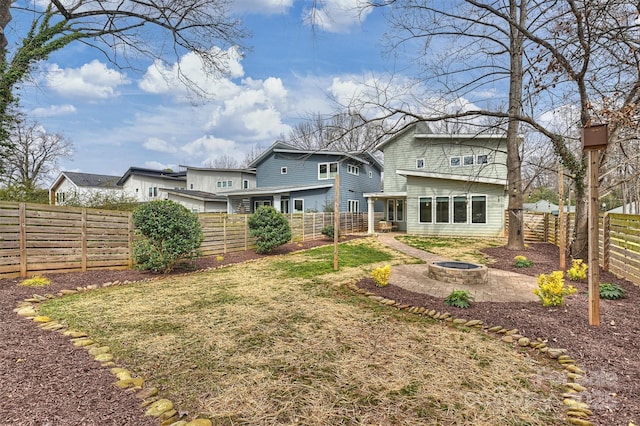 rear view of property with a yard and an outdoor fire pit