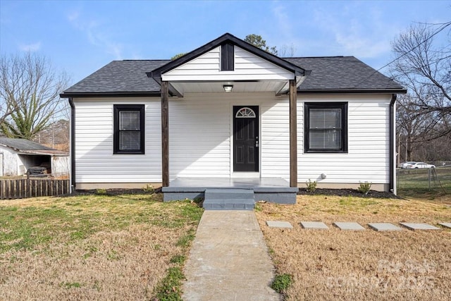 bungalow-style home featuring fence, a front lawn, and a shingled roof