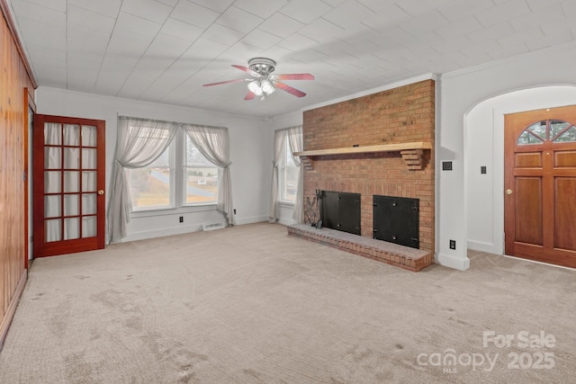 unfurnished living room with ornamental molding, light carpet, ceiling fan, and a fireplace