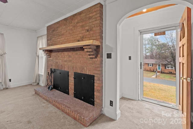 carpeted living room with ornamental molding and a brick fireplace