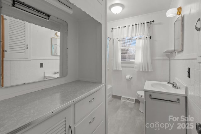 bathroom featuring vanity, ornamental molding, tile walls, and toilet