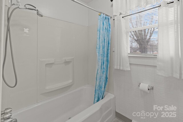 bathroom featuring shower / bath combo with shower curtain and tile walls