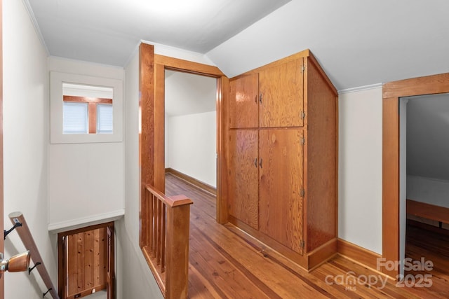 hall with crown molding, vaulted ceiling, and light wood-type flooring