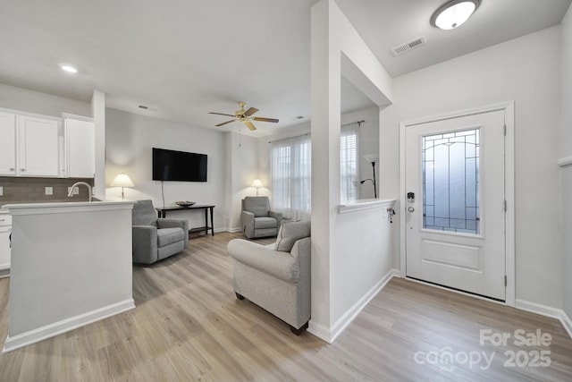 foyer entrance with ceiling fan, sink, and light hardwood / wood-style floors