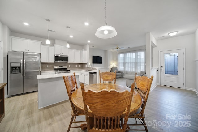 dining space with ceiling fan, sink, and light wood-type flooring