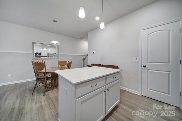 kitchen featuring pendant lighting, light hardwood / wood-style floors, white cabinets, and a kitchen island