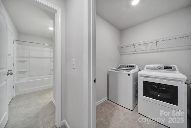 laundry area with separate washer and dryer and light tile patterned floors