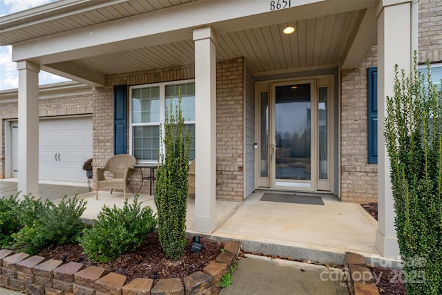 view of exterior entry with a garage and a porch