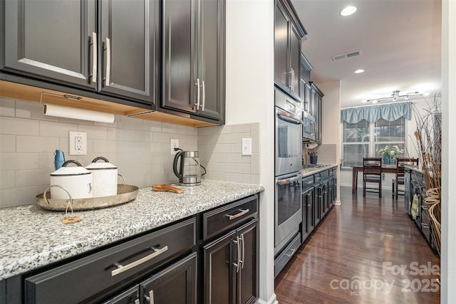 kitchen with dark hardwood / wood-style flooring, light stone counters, decorative backsplash, and stainless steel gas stovetop