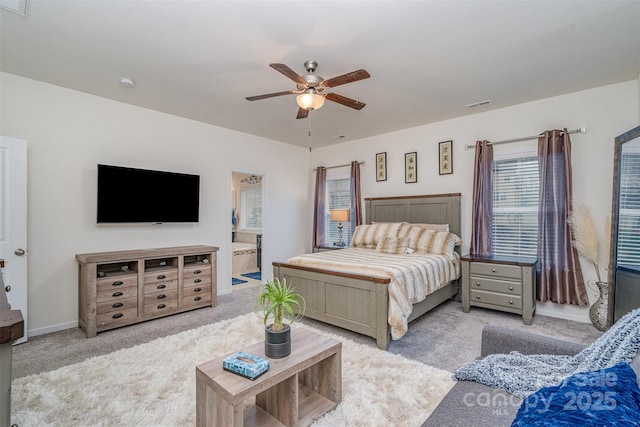 bedroom with ceiling fan, ensuite bath, and light carpet