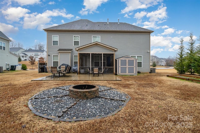 back of property with a storage shed, a fire pit, cooling unit, a patio area, and a sunroom