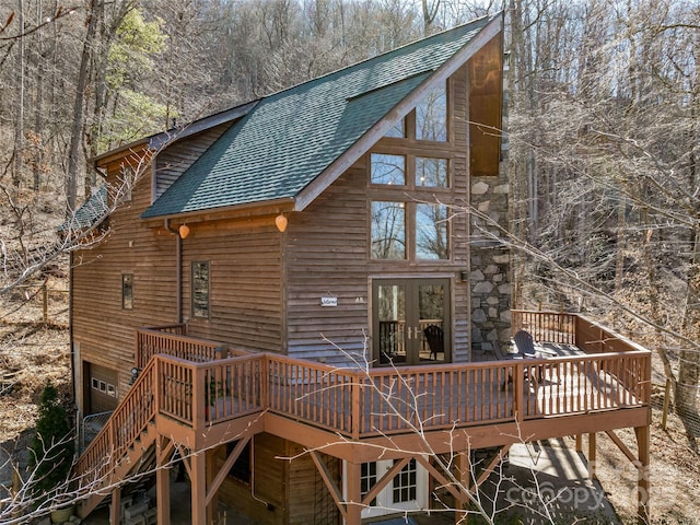 rear view of property with a shingled roof, french doors, and a wooden deck