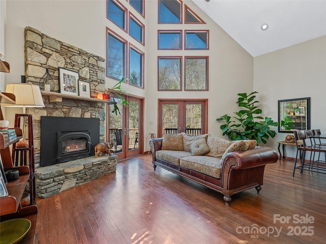 living area featuring french doors, a fireplace, hardwood / wood-style flooring, and baseboards